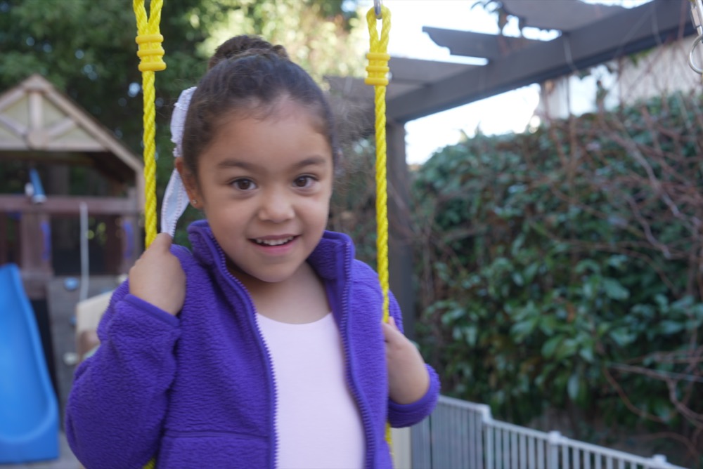 Child playing on a swing at Little Explorers weekend program